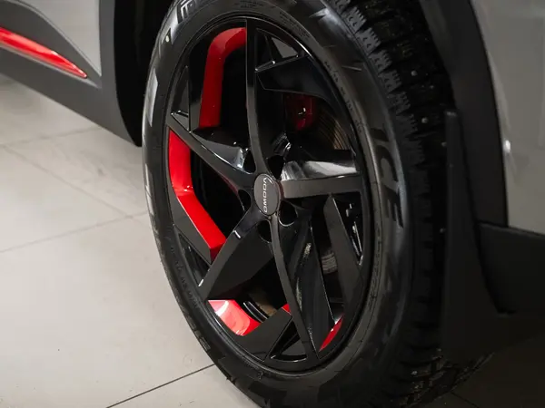 Чёрный литой диск с красными суппортами на автомобиле после антихром-обработки