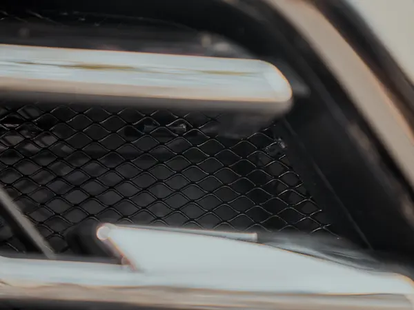 Хромированный молдинг бампера с чёрной сеткой за ним, крупный план детали