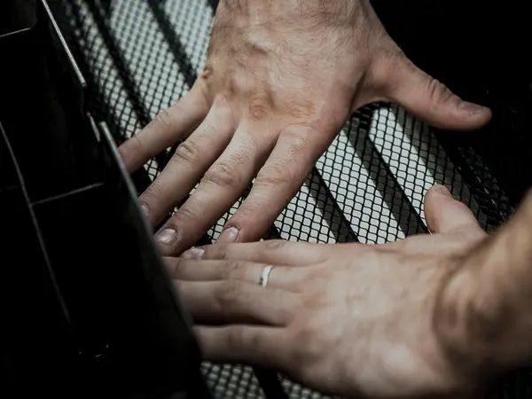 Мастер прижимает чёрную сетку к решётке бампера двумя руками при оклейке