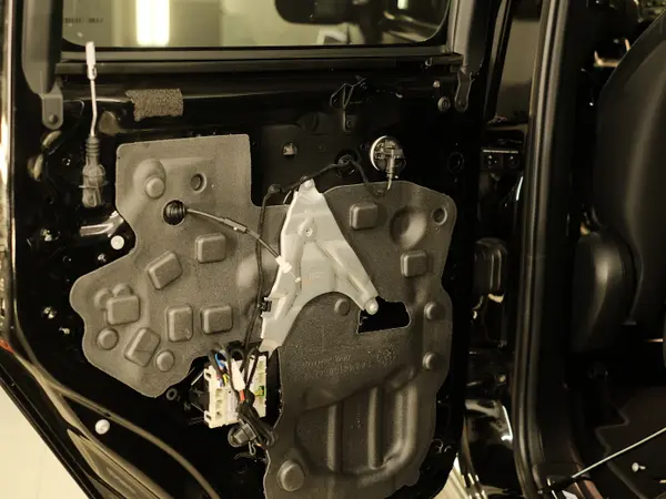 Внутренняя часть двери автомобиля со снятой обшивкой, виден механизм доводчика и проводка