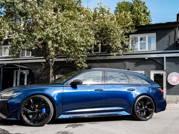 Синий Audi RS Q8 после детейлинг-мойки, вид сбоку на фоне здания