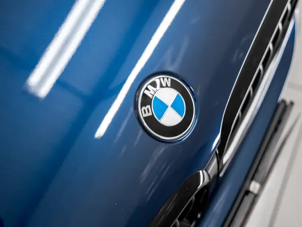 Эмблема BMW на капоте синего автомобиля после полировки с нанесением керамики — глубокий глянец