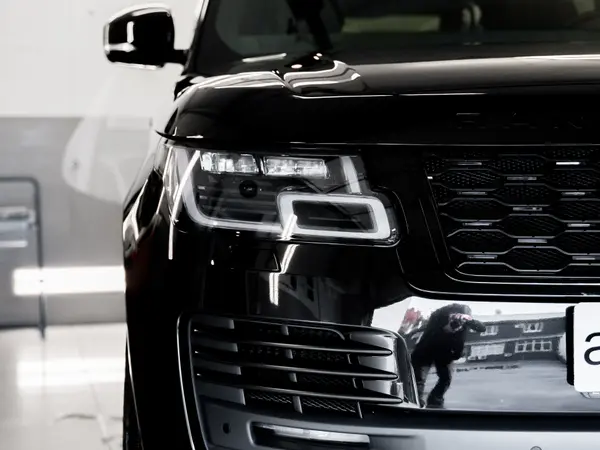 Передняя часть чёрного Range Rover после полировки жидким стеклом — зеркальный блеск фар и решётки