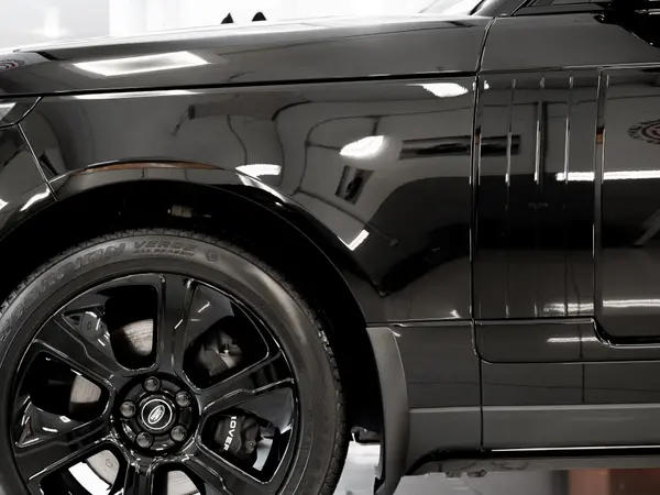 Чёрный Range Rover после нанесения жидкого стекла — глянцевое крыло и колёсный диск крупным планом