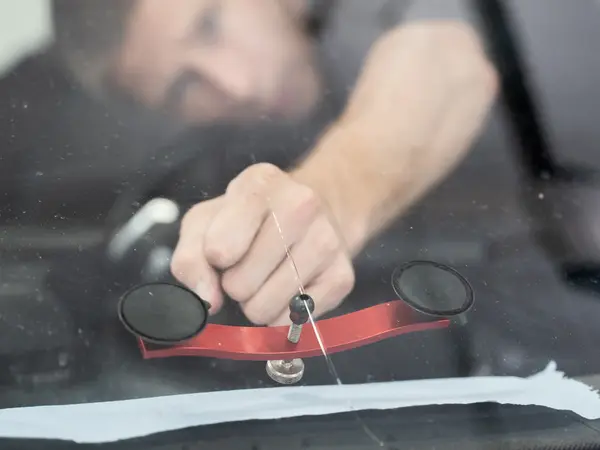 Мастер устанавливает мост-инжектор с присосками на лобовое стекло для ремонта скола