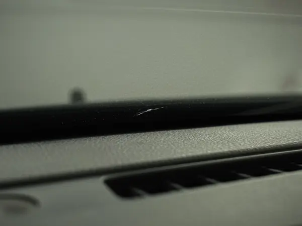 Мелкий скол у нижнего края лобового стекла, вид из салона на торпедо